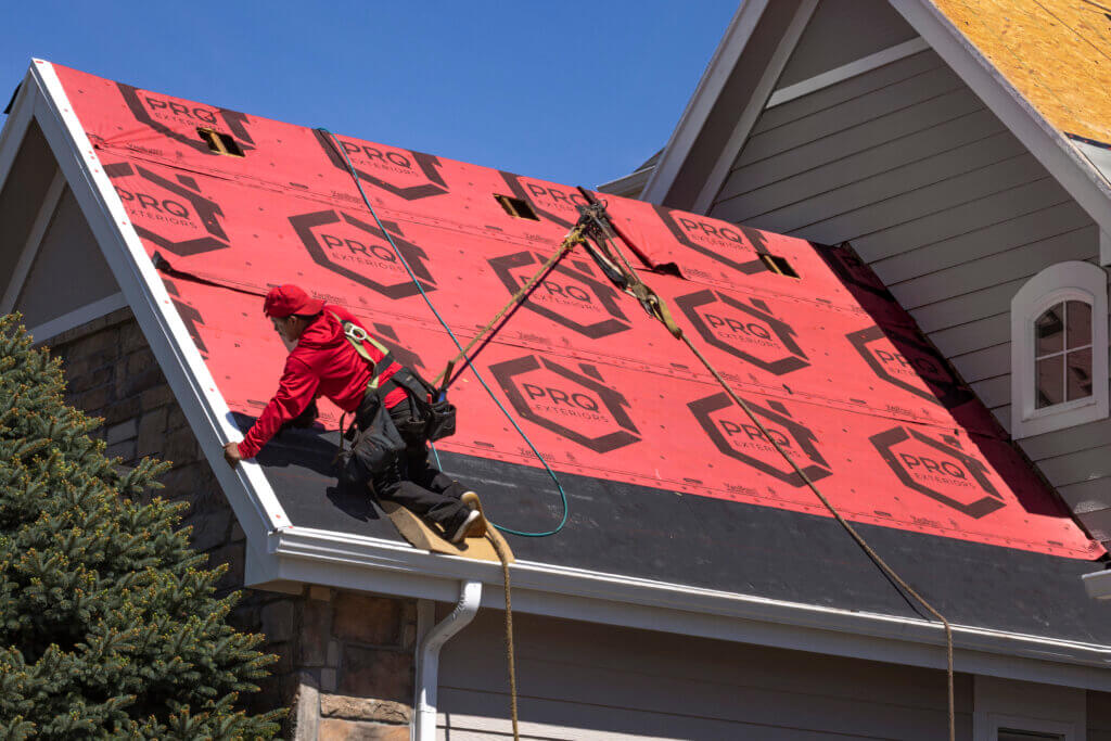 PRQ roofer installing PRQ-branded synthetic underlayment over a sealed roof deck